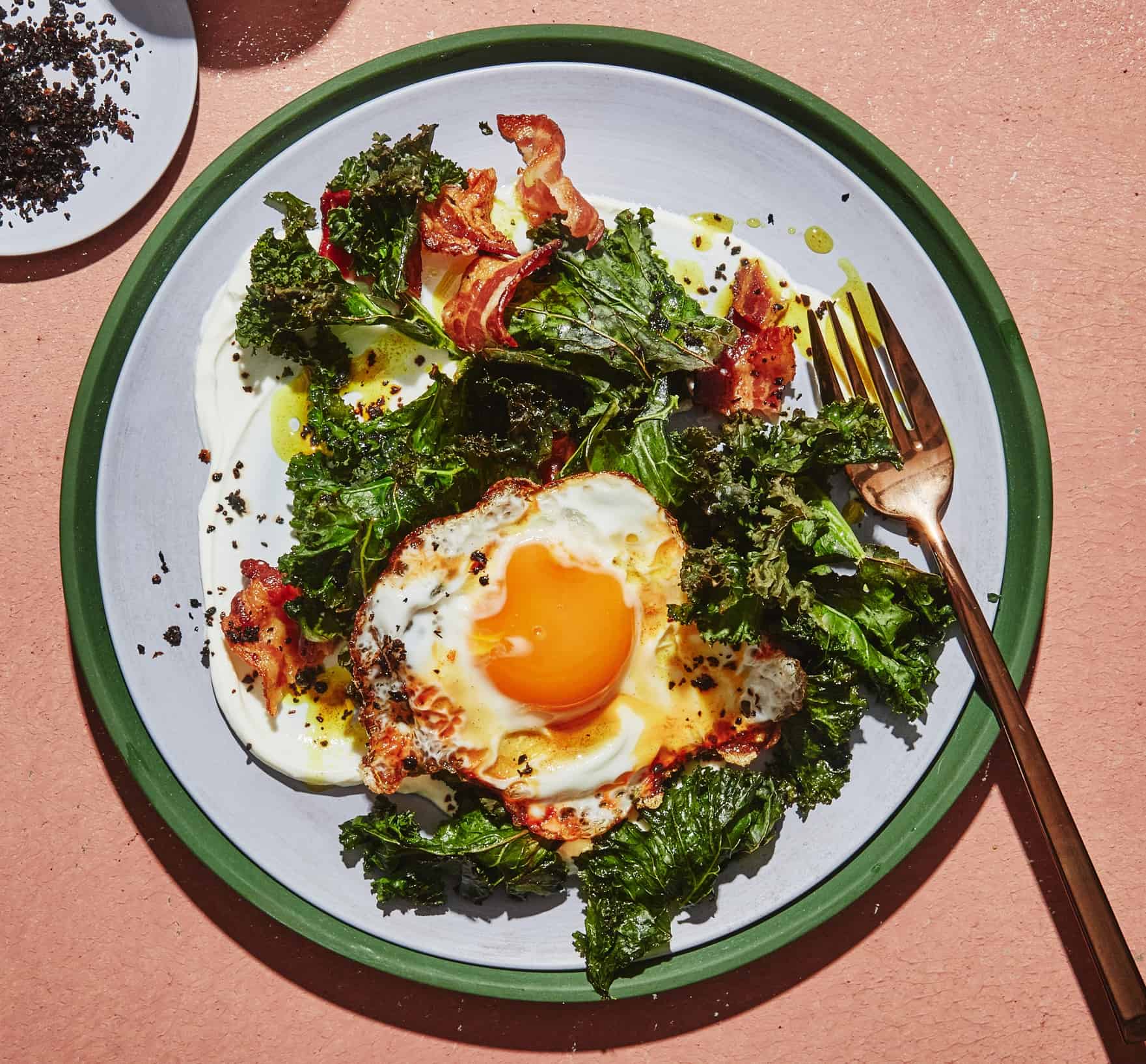 a plate of turmeric fried egg and bacon with kale